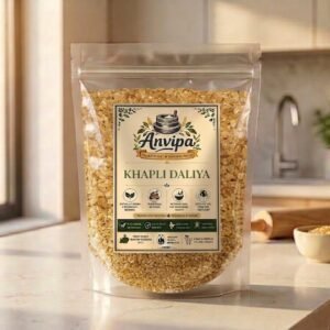 A premium pouch of Anvipa chemical-free Khapli Daliya next to a rustic bowl of raw broken emmer wheat, showing clean natural breakfast grains.