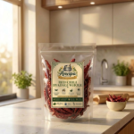 A premium pouch of Anvipa chemical-free Pure Whole Byadagi Red Chilli beside a small bowl filled with sun-dried, deeply crinkled crimson whole red chilli pods.