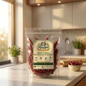 A premium pouch of Anvipa chemical-free Pure Whole Byadagi Red Chilli beside a small bowl filled with sun-dried, deeply crinkled crimson whole red chilli pods.