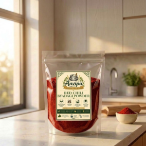 A premium pouch of Anvipa chemical-free Pure Byadagi Red Chilli Powder beside a small terracotta bowl filled with cold ground deep crimson-red lal mirch.