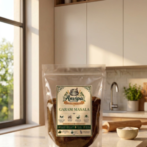 A premium pouch of Anvipa chemical-free Pure Garam Masala Powder beside a small terracotta bowl showing stone ground warm brown spice mix.