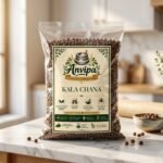A premium pouch of Anvipa chemical-free Pure Desi Kala Chana beside a small wooden scoop showing raw, unpolished, and textured brown-black chickpeas.
